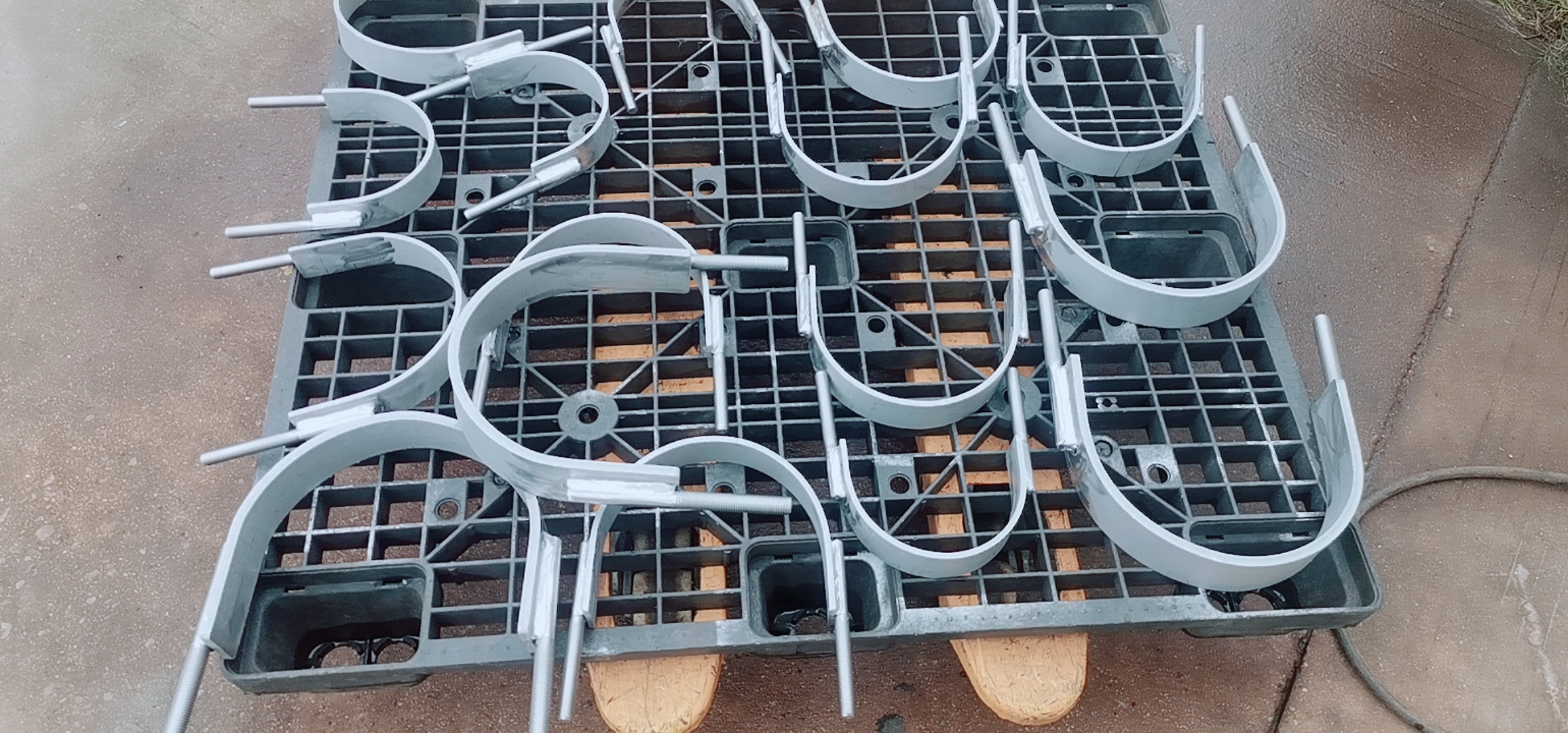 Flat Steel U-Bolt Clamps – Factory Production Multiple fabricated flat steel U-bolt clamps with welded threaded studs on a factory pallet
